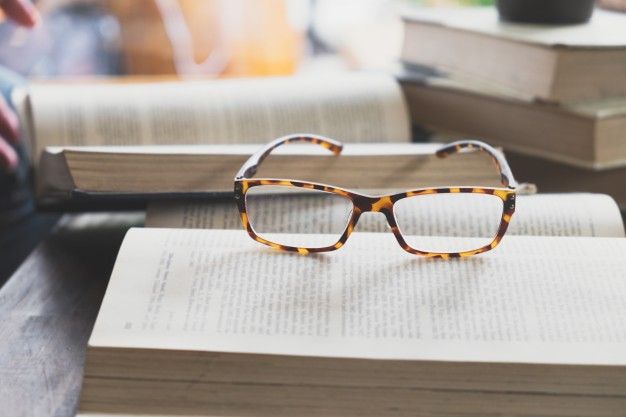 glasses-on-opening-book-in-library-or-ca